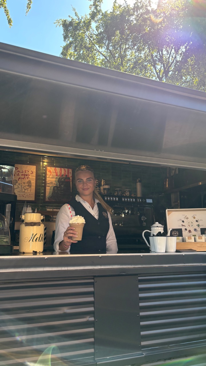 Barista serveert ijskoffie met slagroom vanuit mobiele koffiebar