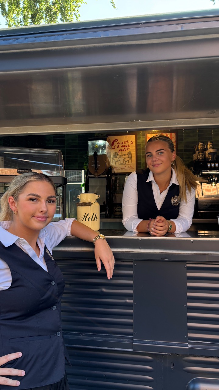 Twee serveersters bij een koffiekraam
